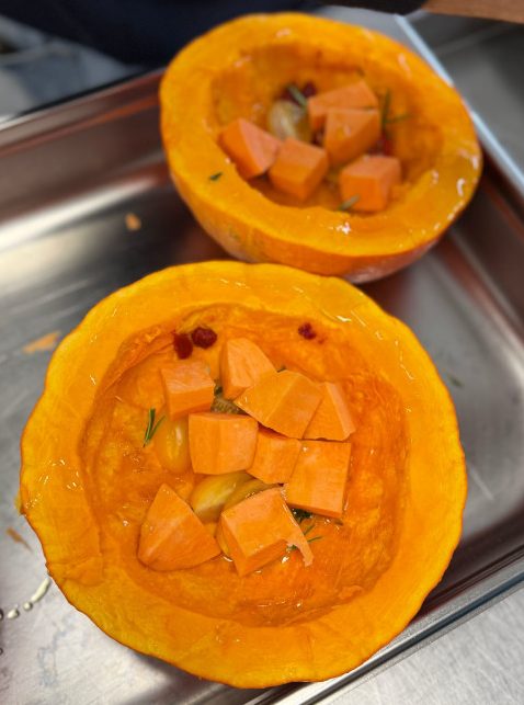 Pompoen in twee delen en gevuld met kruiden en zoete aardappel